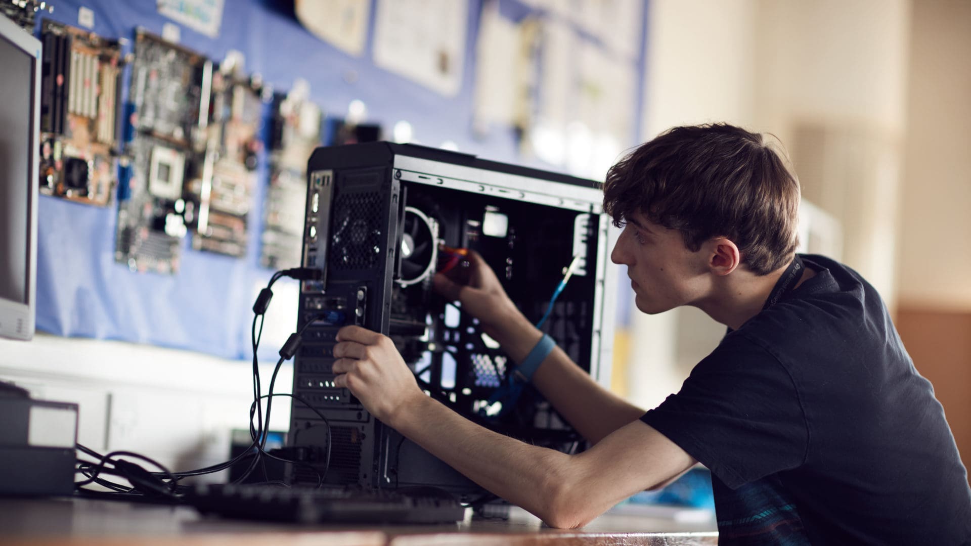 Ӱֱ student focusing on fixing a computer on an IT course
